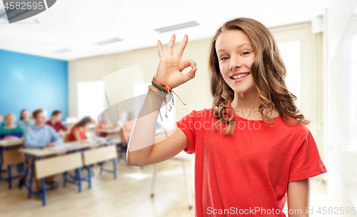 Image of smiling teenage student girl showing ok at school