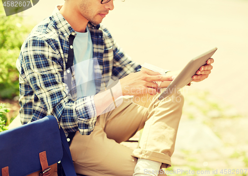 Image of man with tablet pc and coffee on city street bench