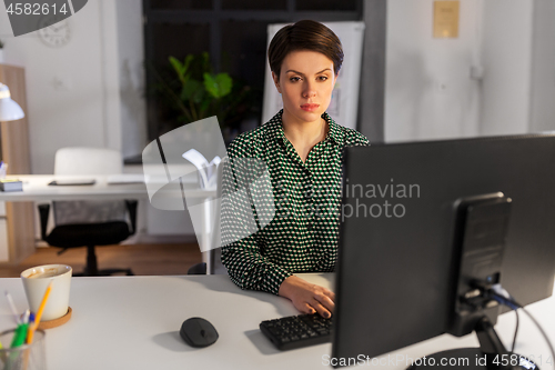 Image of businesswoman working on computer at night office