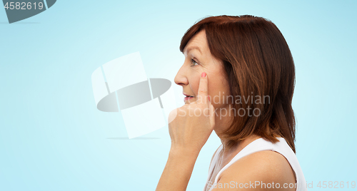 Image of profile of senior woman pointing to eye wrinkles