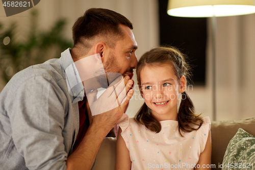 Image of happy father whispering secret to daughter at home