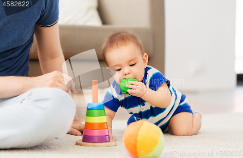 Image of baby boy with father and pyramid toy at home