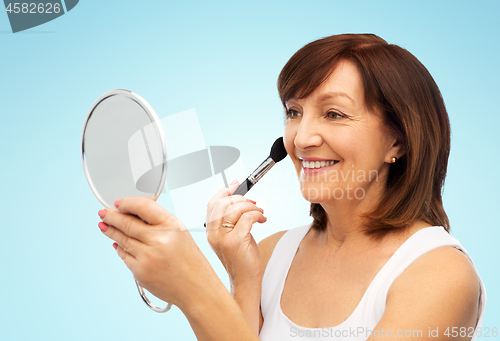 Image of senior woman with mirror and make up blush brush