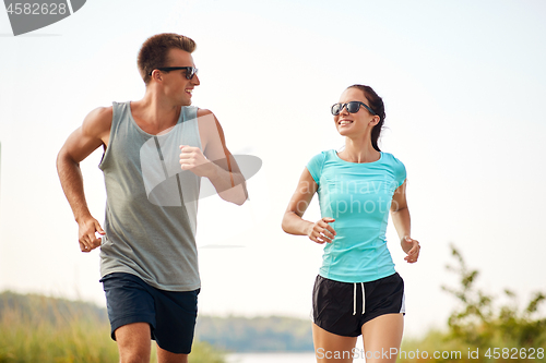 Image of couple in sports clothes running along on beach