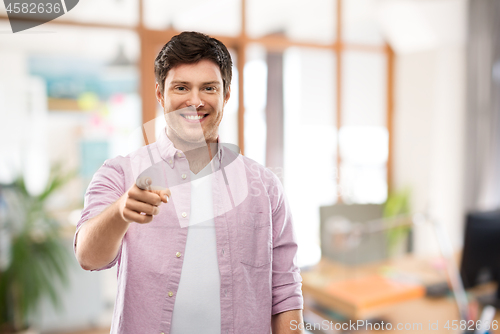 Image of smiling man pointing fingers at you over office