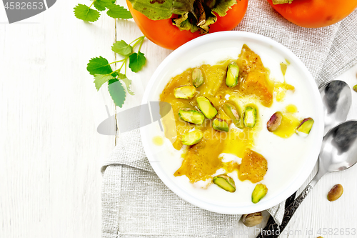 Image of Dessert of yogurt and persimmon in bowl on light board top