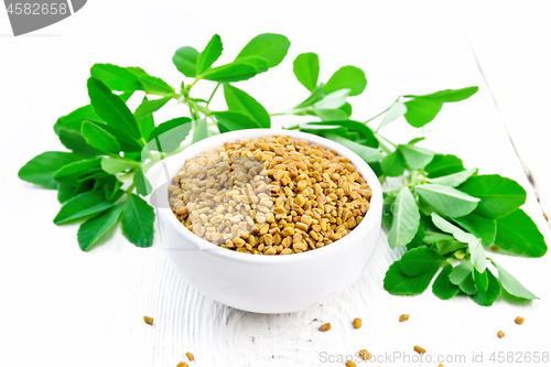 Image of Fenugreek with green leaves in bowl on wooden board
