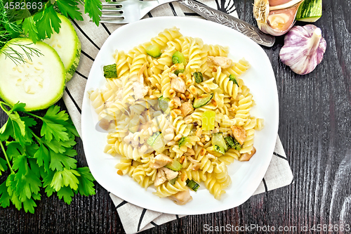 Image of Fusilli with chicken and zucchini in plate on wooden board top