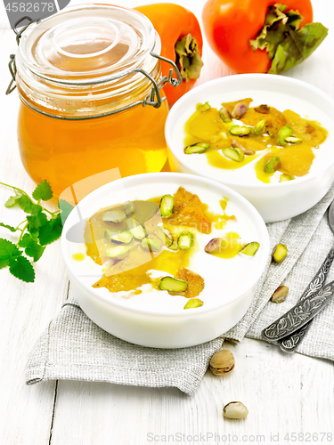 Image of Dessert of yogurt and persimmon two bowls on wooden board