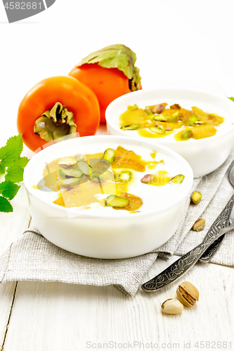 Image of Dessert of yogurt and persimmon two bowls on board