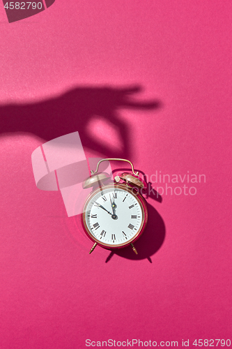 Image of Hand\'s shadows holds retro golden painted alarmclock.