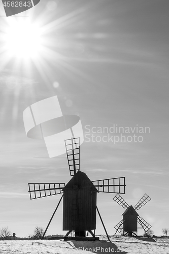 Image of Sun and sunbeams by two old windmills