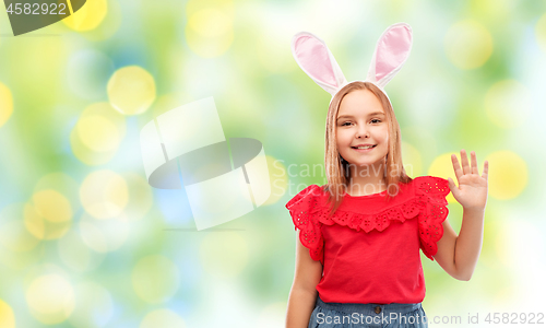 Image of happy girl wearing easter bunny ears waving hand