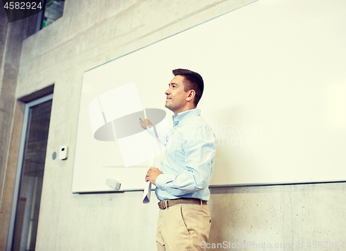 Image of teacher pointing marker to white board at lecture