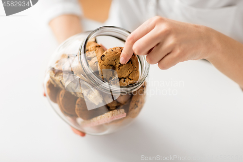 Image of close up of woman taking oatmeal cookies from jar