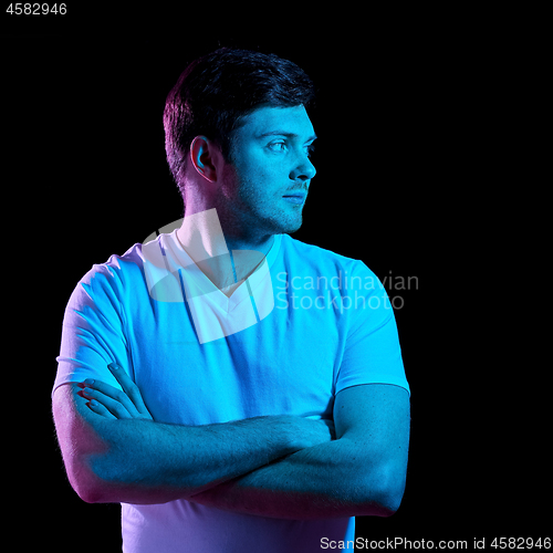 Image of man with crossed arms over neon lights in darkness