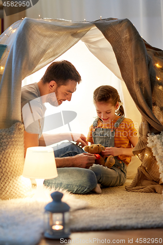 Image of happy family playing with toy in kids tent at home