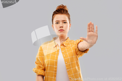 Image of red haired teenage girl making stopping gesture