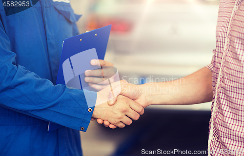 Image of auto mechanic and man shaking hands at car shop