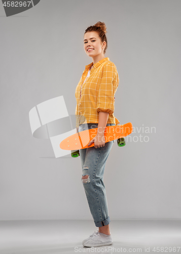 Image of red haired teenage girl with short skateboard