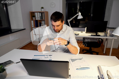 Image of businessman with smartphone and computer at office