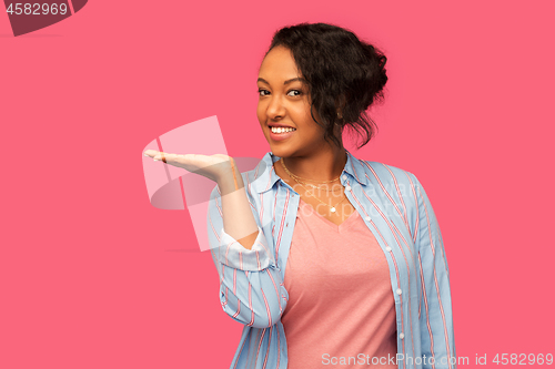 Image of happy african woman holding something on hand