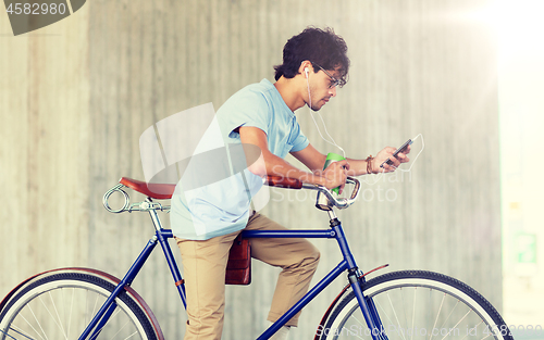 Image of man with smartphone and earphones on bicycle