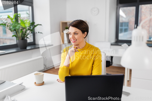 Image of happy businesswoman sitting at office table