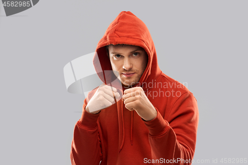 Image of man in red hoodie fighting with fists or boxing