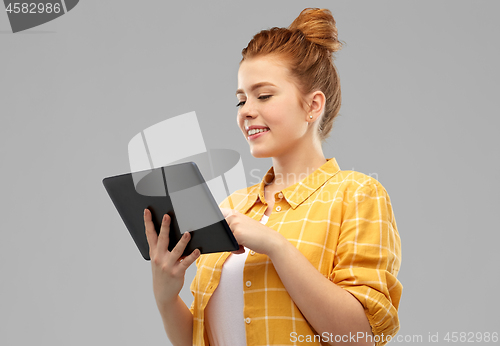 Image of red haired teenage girl using tablet computer