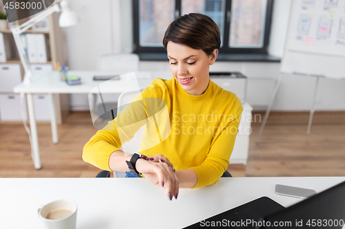 Image of happy businesswoman using smart watch at office