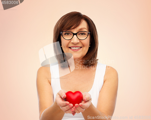 Image of portrait of smiling senior woman holding red heart