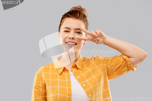 Image of smiling red haired teenage girl showing peace