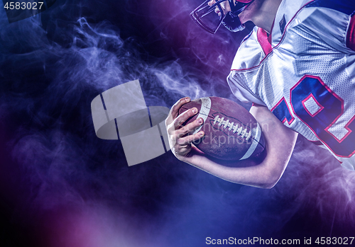 Image of American football player holding ball while running on field