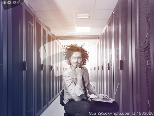 Image of engineer working on a laptop in server room