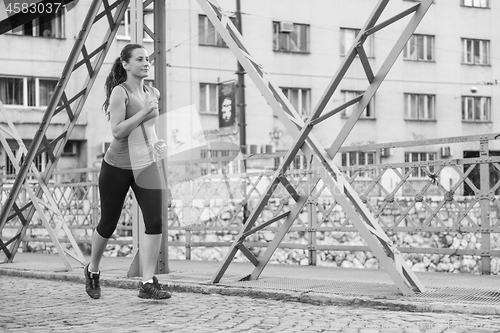 Image of woman jogging across the bridge at sunny morning