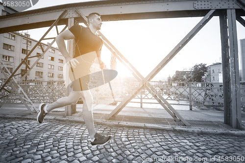 Image of man jogging across the bridge at sunny morning