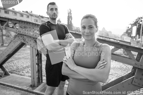 Image of young couple jogging across the bridge in the city