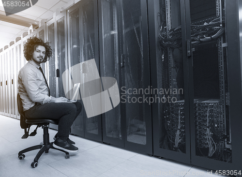 Image of engineer working on a laptop in server room