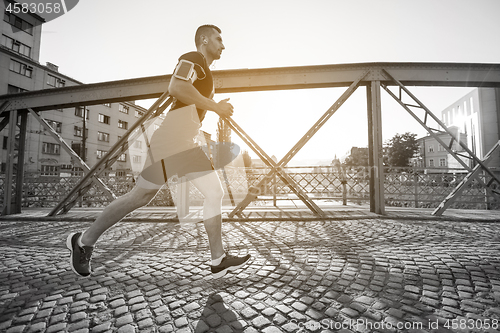 Image of man jogging across the bridge at sunny morning