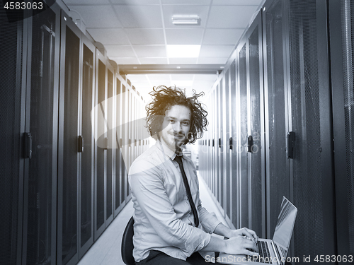 Image of engineer working on a laptop in server room