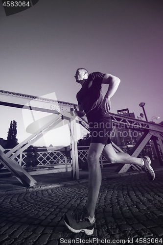 Image of man jogging across the bridge in the city