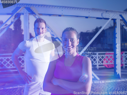 Image of portrait of couple jogging across the bridge in the city