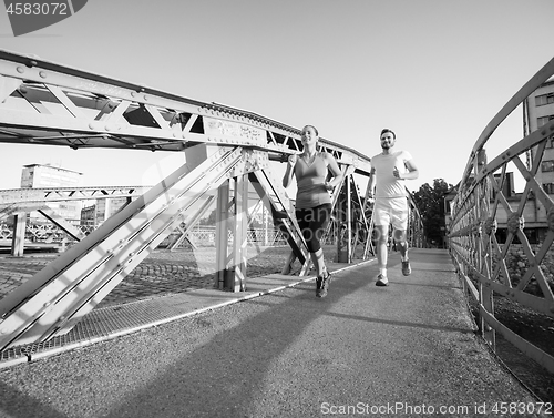 Image of young couple jogging across the bridge in the city