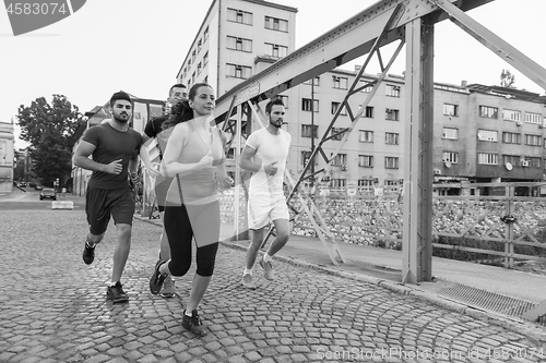 Image of group of young people jogging across the bridge