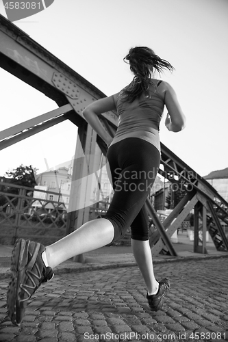 Image of woman jogging across the bridge at sunny morning