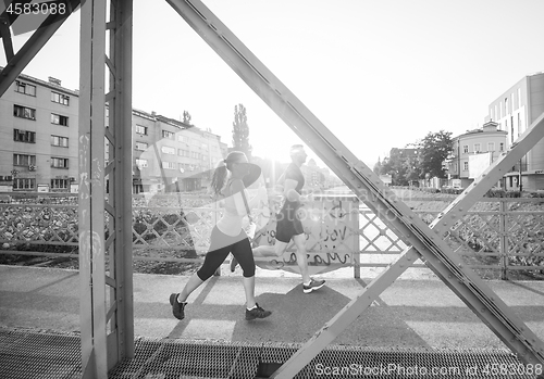 Image of young couple jogging across the bridge in the city