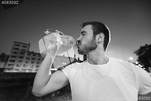 Image of man drinking water after running session