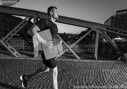 Image of man jogging across the bridge in the city