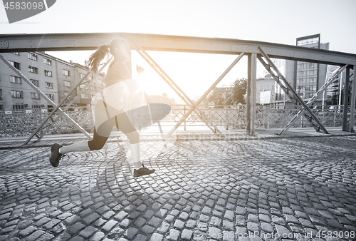 Image of woman jogging across the bridge at sunny morning